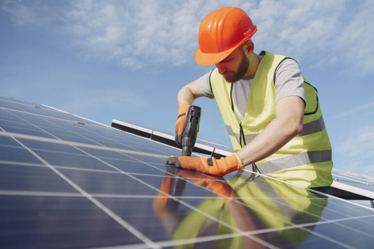 Homem trabalhando com EPI em painel solar após encontrar uma das vagas de emprego para energia solar