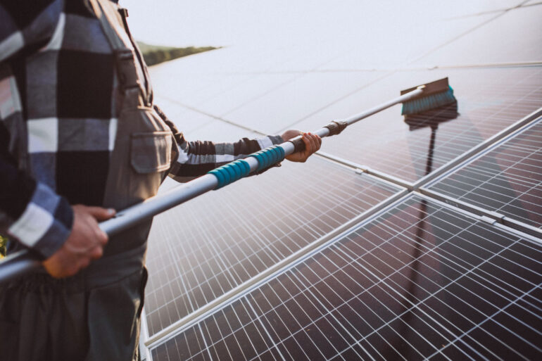 Homem fazendo manutenção de energia solar, limpando os painéis solares.